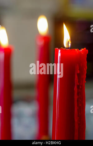viele Gebet rot Brennen lange Kerzen in Budist temple Stockfoto