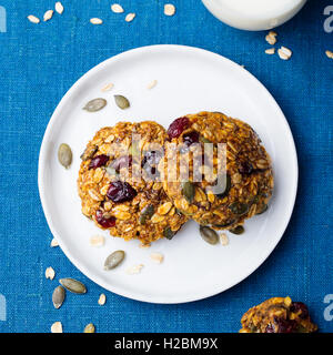 Kürbis-Cookies mit Preiselbeeren und Ahorn Glasur auf einem schwarzen Teller. Draufsicht auf blauem Hintergrund Stockfoto