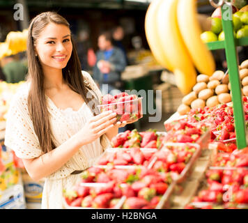 Hübsche junge Frau, die Äpfel auf dem Markt zu kaufen Stockfoto