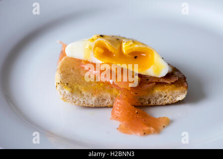 Pochiertes Ei schmelzen in Räucherlachs auf einen Muffin. Stockfoto