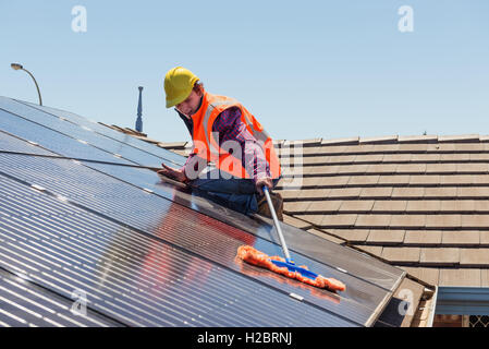 Junge Arbeitnehmer Reinigung Solarzellen auf dem Dach. Konzentrieren Sie sich auf die Arbeitskraft. Stockfoto