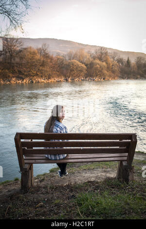 Denken Mädchen auf Bank am Fluss Stockfoto