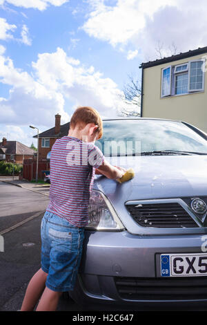 Ein kleiner Junge Autowaschen ein metallisches Silber Vauxhall Meriva außerhalb an einem sonnigen Tag Stockfoto