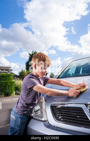 Ein kleiner Junge Autowaschen ein metallisches Silber Vauxhall Meriva außerhalb an einem sonnigen Tag Stockfoto