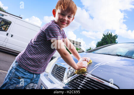 Ein kleiner Junge Autowaschen ein metallisches Silber Vauxhall Meriva außerhalb an einem sonnigen Tag Stockfoto