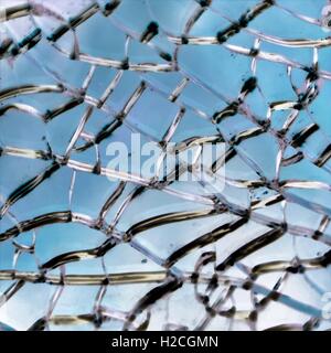 Zerbrochene Glasscheibe dick mit blauem Hintergrund. Stockfoto