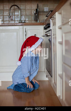 Neugierige kleine Junge, gerade Lebkuchen Cookies im Ofen backen für Weihnachten Stockfoto