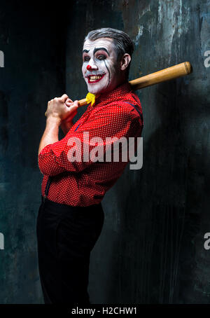 Die beängstigend Clown und Baseballschläger auf Dack Hintergrund. Halloween-Konzept Stockfoto