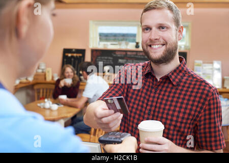 Kunden zahlen für Kaffee zum Mitnehmen mit kontaktlosen Terminal Stockfoto