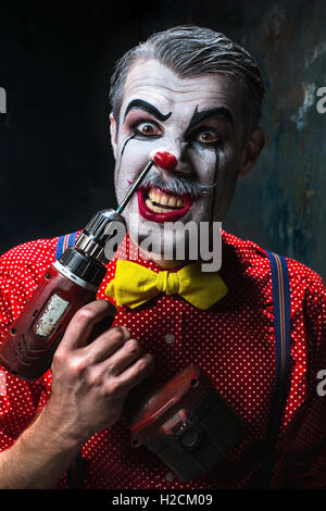 Die beängstigend Clown und Bohrmaschine auf Dack Hintergrund. Halloween-Konzept Stockfoto