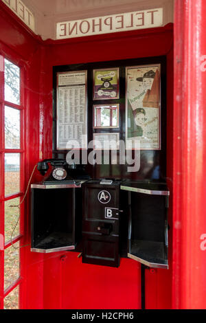 Innenraum der 1930er Jahre traditionelle britische rotes Telefon mit dem ursprünglichen Telefon Ausstattung und Poster. Stockfoto