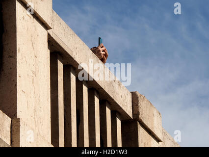 isolierte Hände mit Handy auf Brüstung der Betonbrücke gesprenkelten blauen Himmel Stockfoto