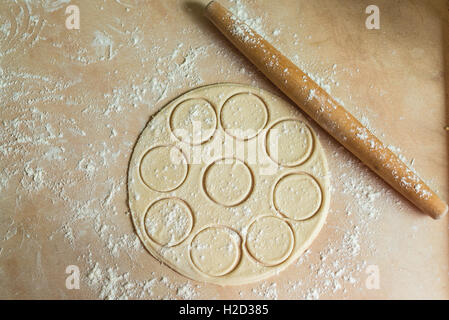 Der Teig gerollt mit Kreisen und Nudelholz für gemachte Ravioli auf einem Holztisch Stockfoto