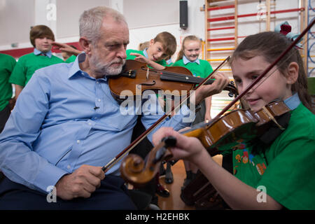 Labour-Chef Jeremy Corbyn erhält eine Geigenunterricht durch 10 jährige Jessica Kelly während eines Besuchs zu glauben Primary School in Liverpool, lernte er die Kinder, die Teilnahme an den In Harmony-Projekt, das stützt sich auf das Royal Liverpool Philharmonic Orchestra und hilft SchülerInnen und Schüler lernen, Musikinstrumente zu spielen. Stockfoto