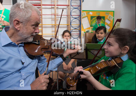 Labour-Chef Jeremy Corbyn erhält eine Geigenunterricht durch 10 jährige Jessica Kelly während eines Besuchs zu glauben Primary School in Liverpool, lernte er die Kinder, die Teilnahme an den In Harmony-Projekt, das stützt sich auf das Royal Liverpool Philharmonic Orchestra und hilft SchülerInnen und Schüler lernen, Musikinstrumente zu spielen. Stockfoto