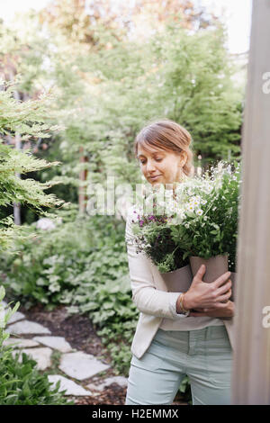 Porträt einer lächelnden Frau trägt eine Reihe von weißen Blüten. Stockfoto