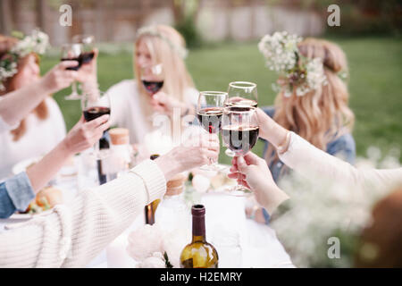 Gruppe von Freundinnen versammelten sich an einem Tisch, toasten, mit Rotwein ablöschen. Stockfoto