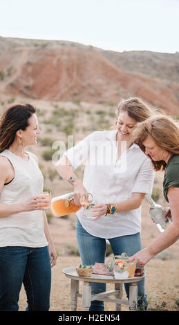 Drei Frauen stehen in einer Wüstenlandschaft mit einem Drink. Stockfoto