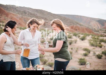 Drei Frauen stehen in einer Wüstenlandschaft mit einem Drink. Stockfoto