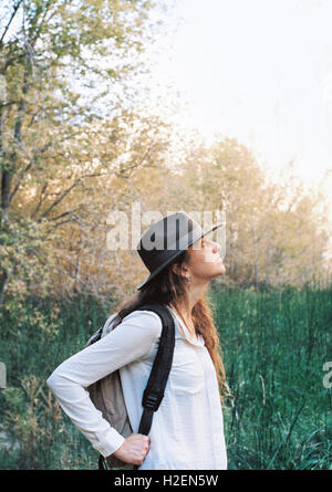 Eine Frau mit einem Hut mit breiter Krempe und Baackpack im Wald im Sommer. Stockfoto