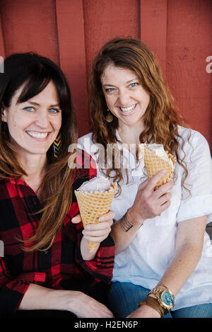 Zwei Frauen sitzen auf einer Bank, Eis essen. Stockfoto
