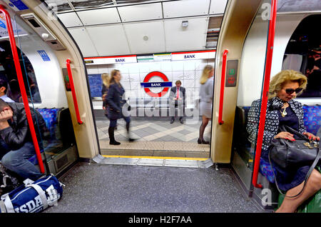 London, England, Vereinigtes Königreich. Londoner U-Bahn u-Bahnstation: Zugtüren geöffnet an Bank Station - Geschäftsmann auf der Plattform-Lesung Stockfoto