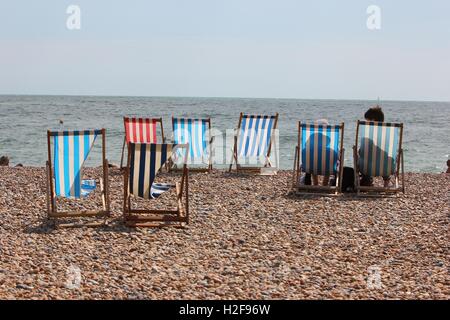 Bunt gestreiften Strand Liegestühle auf den gepflasterten Strand, Brighton, England Stockfoto