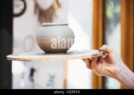 Ein Töpfer hält ein prefired Topf auf einem Brett neu geworfen. Stockfoto