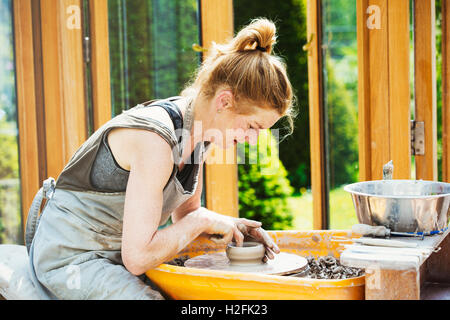 Eine Frau Töpfer arbeiten Ton auf einer Töpferscheibe in ihrer Werkstatt. Stockfoto