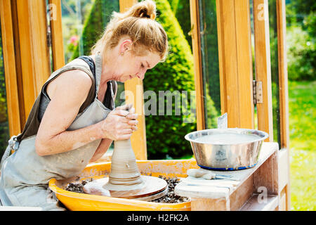 Eine Frau Töpfer arbeiten Ton auf einer Töpferscheibe in ihrer Werkstatt. Stockfoto