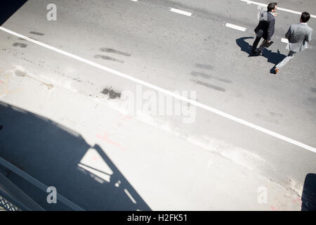 Erhöhte Ansicht von zwei Geschäftsleute in grauen Anzügen überqueren einer Straße in New York. Stockfoto