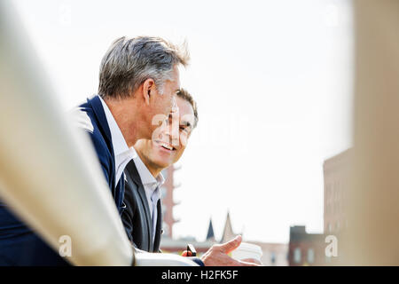 Zwei Menschen, Männer, die miteinander reden im freien stützte sich auf ein Geländer, eine Kaffee-Pause. Stockfoto