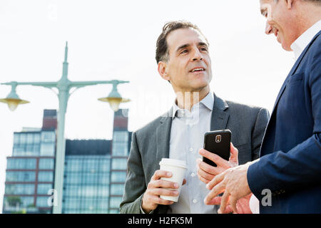 Zwei Menschen, Männer, die miteinander reden im freien stützte sich auf ein Geländer, eine Kaffee-Pause. Stockfoto