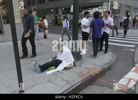 Obdachlose Menschen sitzen auf dem Bürgersteig betteln ist ein alltäglicher Anblick in Midtown Manhattan, einem der reichsten Einkaufsstraßen der Welt. Stockfoto