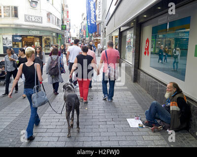 Straßenszene mit großer Hund und Vagabund auf Einkaufsstraße in Köln, Deutschland Stockfoto