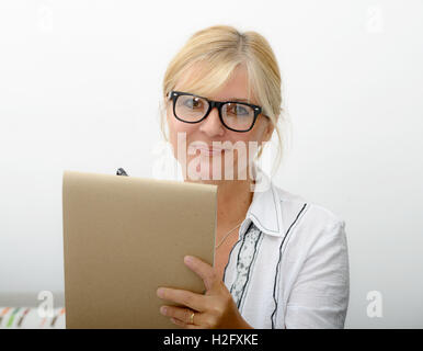 eine reife Frau, die auf einem Notebook zu schreiben Stockfoto