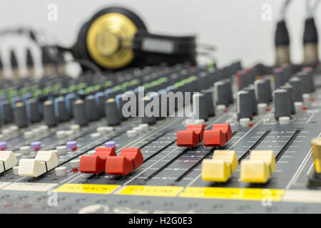 Foto einer Fader Mixer rote Farbe, aufgenommen mit einer geringen Schärfentiefe hautnah. Hintergrund-Geräte und Kopfhörer. Stockfoto