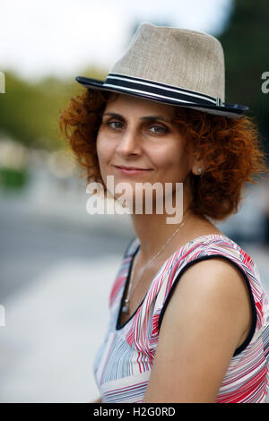 Nahaufnahme einer rothaarige Frau mit Hut in einem städtischen Umfeld Stockfoto