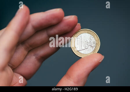 Business Frau Holding ein-Euro-Münze zwischen den Fingern, Nahaufnahme mit selektiven Fokus Stockfoto