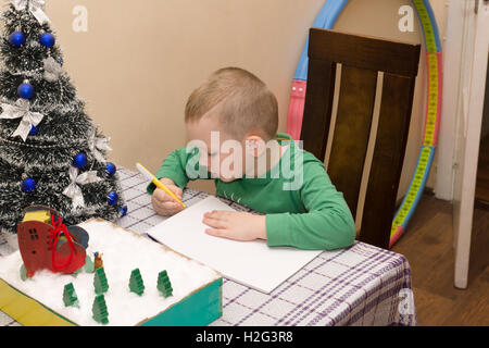 Junge schreibt einen Brief an den Weihnachtsmann brachte ihm Geschenke Stockfoto