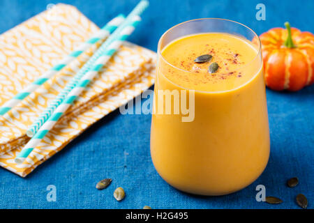 Kürbis Smoothie mit Kürbiskuchen Gewürze auf einem blauen Hintergrund aus Holz Stockfoto