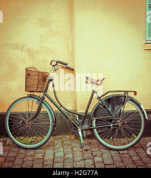 Eine einzigartige grüne Rad anliegt eine leuchtend gelbe Wand illustrieren Kopenhagen Dänemark romantische Fahrradkultur. Stockfoto