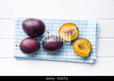 Halbierte reife Pflaumen am Küchentisch. Ansicht von oben. Stockfoto