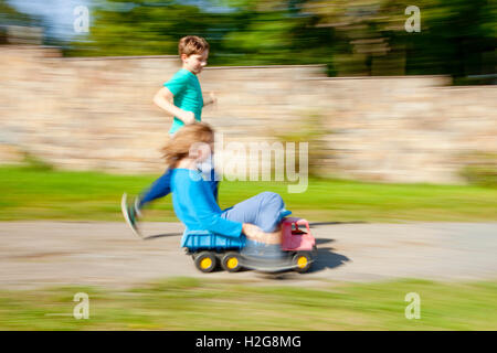 Zwei jungen fahren bergab auf Spielzeug LKW Stockfoto