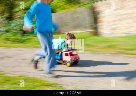 Zwei jungen fahren bergab auf Spielzeug LKW Stockfoto