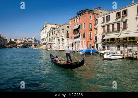 Gondel auf dem Canal Grande mit touristischen Passagieren in Venedig Annäherung an Brücke über den Canal Grande. Ende Sommer, blauer Himmel Stockfoto