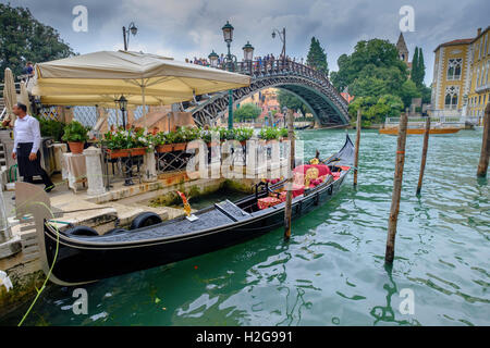 Venedig. Restaurant mit Ankern Gondel in der Nähe von Accademia-Brücke am Canal Grande. Touristen-Pizzeria. Liegeplatz-Stangen im Wasser. Stockfoto