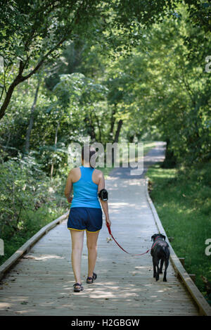 Frau, trägt Fitness-Tracker, und Hund zu Fuß auf einem Pfad Stockfoto