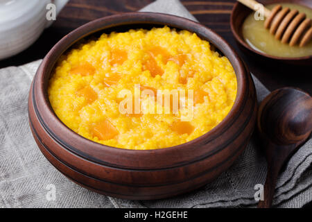 Hirsebrei mit Kürbis in einer Ton-Schüssel auf einem rustikalen hölzernen Hintergrund. Stockfoto