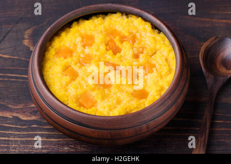 Hirsebrei mit Kürbis in einer Ton-Schüssel auf einem rustikalen hölzernen Hintergrund. Stockfoto